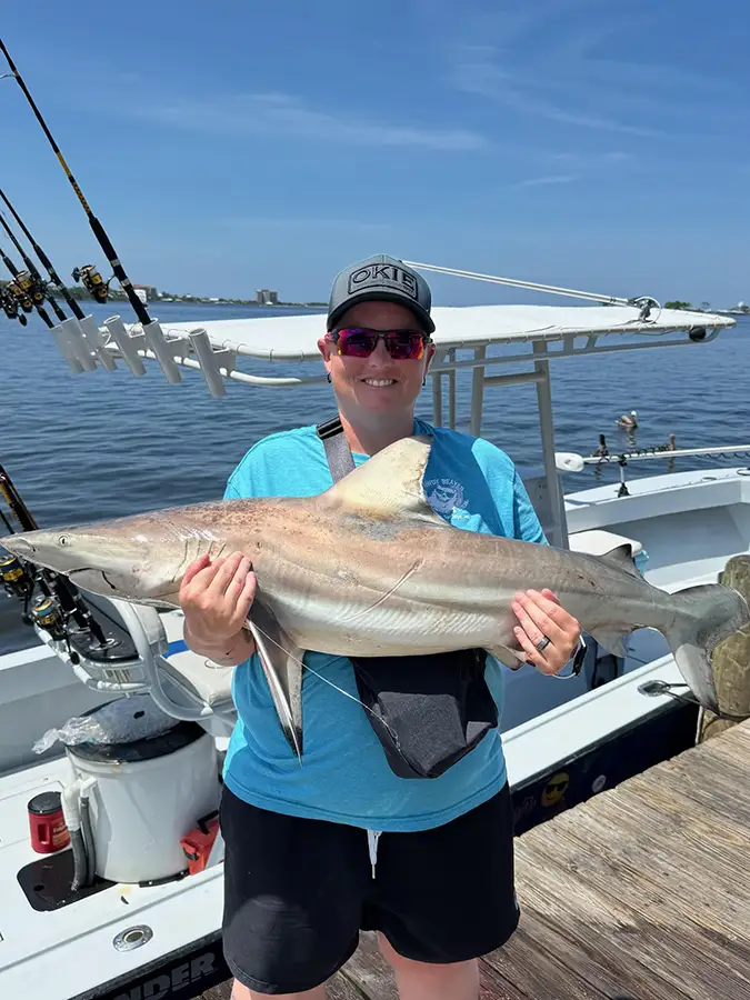 Angler holding a shark on a fishing boat at the dock